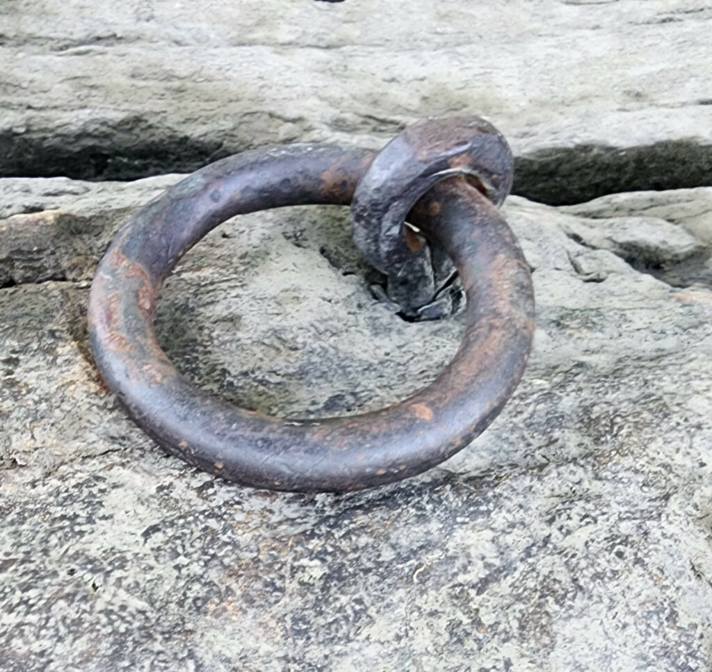 Rusty metal ring attached to a rocky surface.