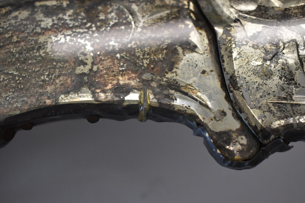Close-up of a corroded metallic surface with silver, rust, and oxidation.