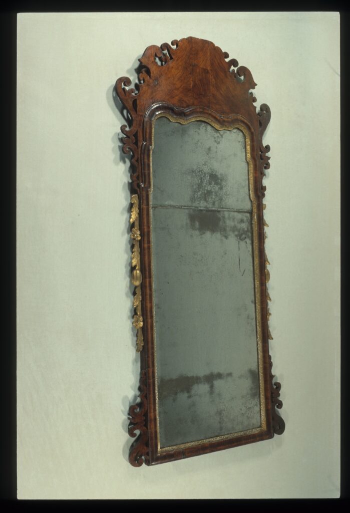 Ornate vintage wall mirror with a carved wooden frame and golden embellishments.