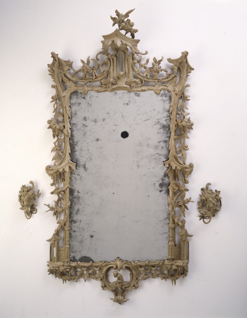 Ornate antique mirror with a decorative Rococo-style frame and aged surface.