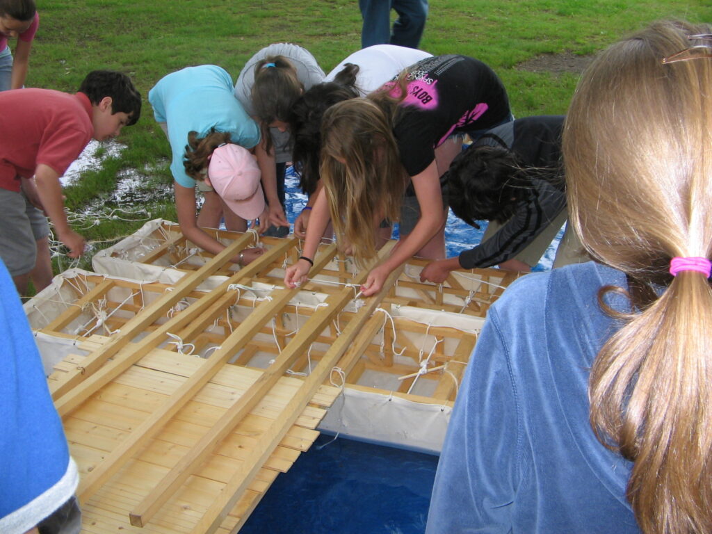 Students work together to construct a pontoon bridge.