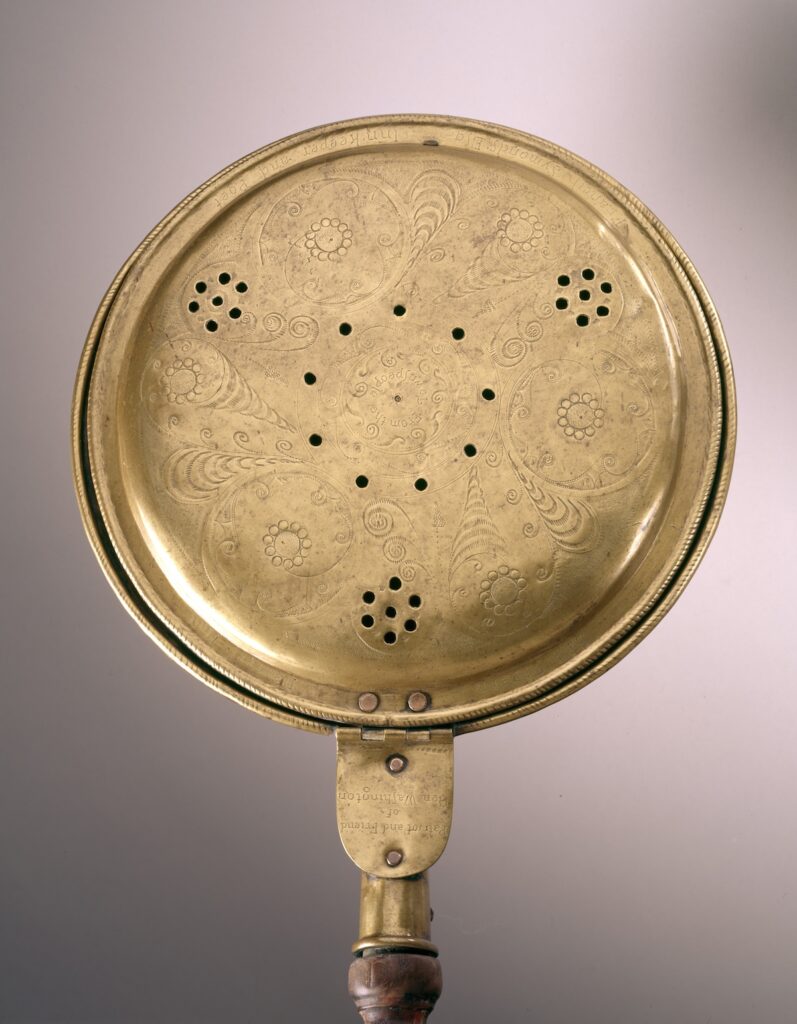 Ornate brass bed warmer with engraved lid and wooden handle. Transcribed Text: Around the lid: "DJ Thornbury, The Harper, Bath 1808." On the hinge: "Barton and Found of Scar."