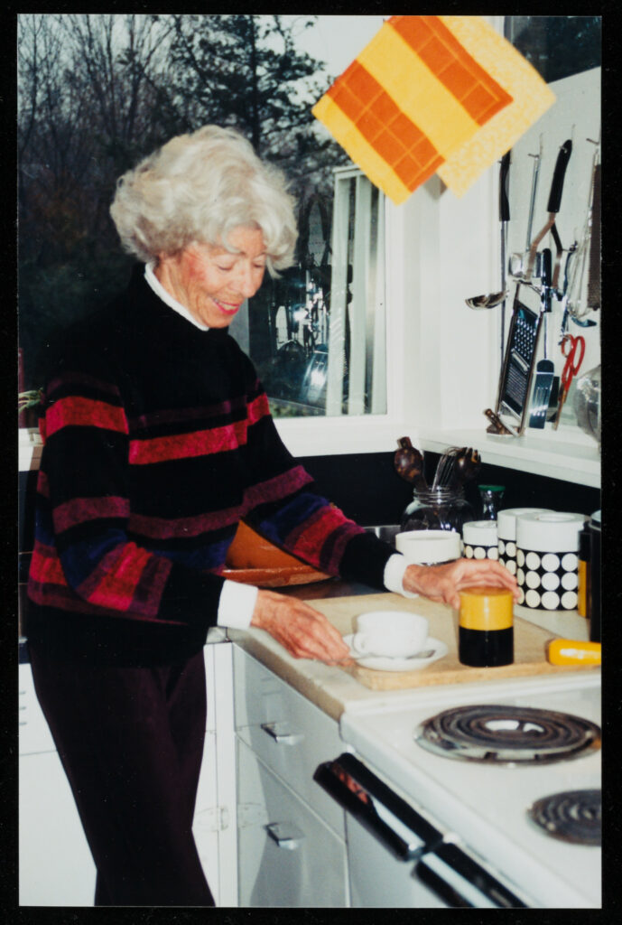 Woman in a kitchen reaching for a cup on a countertop.