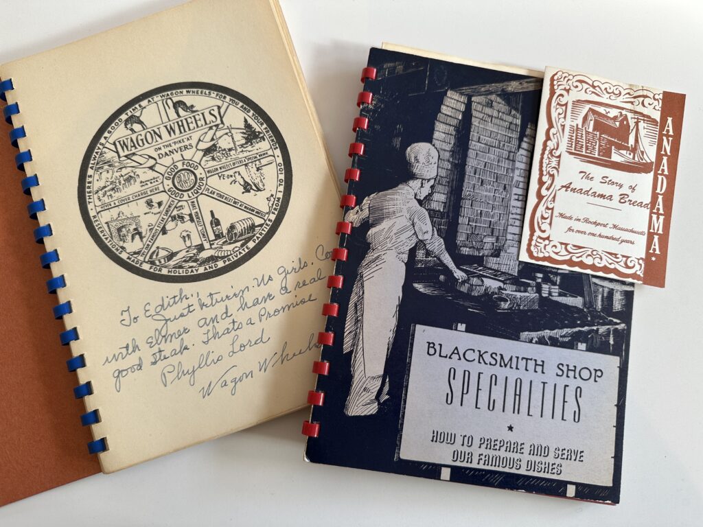 Two vintage cookbooks with spiral bindings, one titled "Wagon Wheels" with a tan cover and the other titled "Blacksmith Shop Specialties" with a black and white cover. Transcribed Text: Left Cookbook (Wagon Wheels): WAGON WHEELS A WHEEL OF FOOD TANENCIOS DANVERS MUSSOL FORTUNE * BLICKUIRY HOLIDAY FOODS FOR THE HOLIDAY FEAST To Edith Ferriter, "Ma Jolie", with More and Love and a good stalk. That's a promise. Phyllis Lord Wagon Wheels Right Cookbook (Blacksmith Shop Specialties): BLACKSMITH SHOP SPECIALTIES HOW TO PREPARE AND SERVE OUR FAMOUS DISHES Small Booklet: ANADAMA The Story of Anadama Bread Made in Rockport - Massachusetts Famous throughout New England