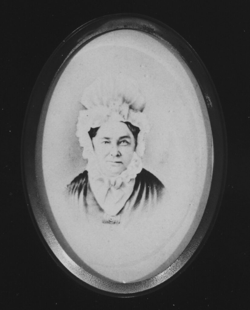 Oval-framed black and white photograph of a woman in a bonnet from the 19th century.
