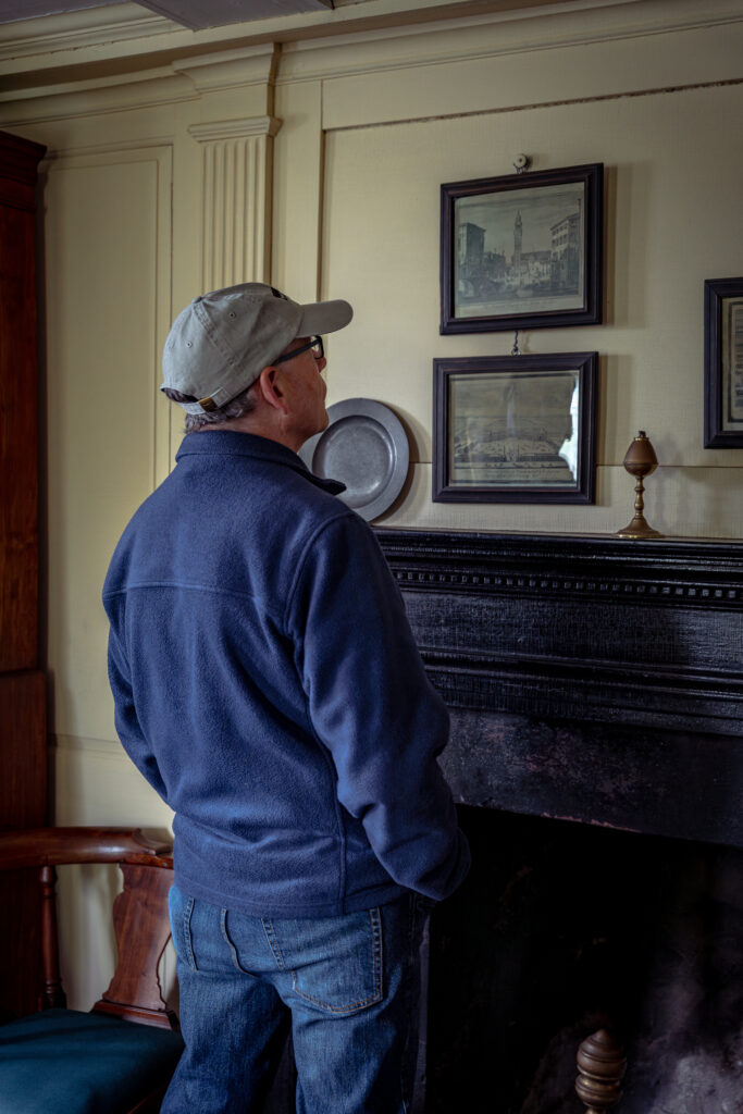Docent leads a museum tour in a historic, lushly decorated room with period portraits on wallpapered walls.
