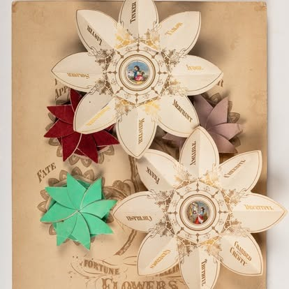 Decorative paper flowers with intricate Victorian designs and text, adorned with a central illustration on a vintage backdrop.