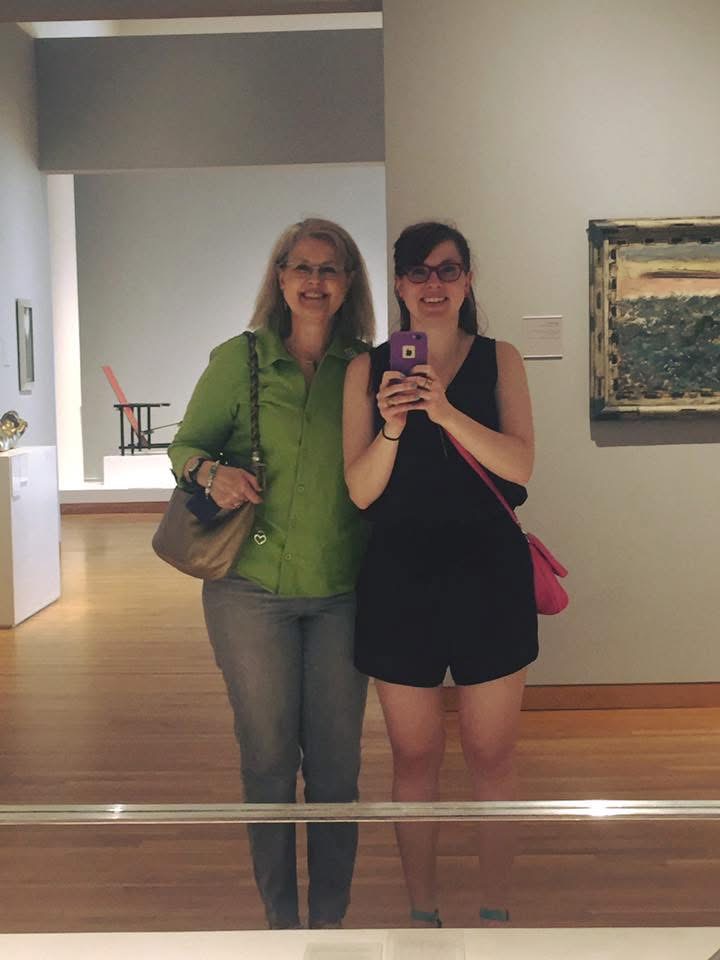 Two visitors stand in a modern art gallery, surrounded by minimalistic design and artwork.