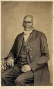 Sepia portrait of an older man in 1800s attire, sitting, looking towards the camera with a neutral expression.