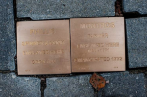 Memorial plaques on a brick pathway, honoring Phillis and Montros, enslaved workers, with engraved historical details.