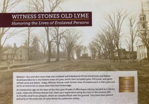 Historic Old Lyme street view honoring enslaved persons with Witness Stones memorial site description and background trees.