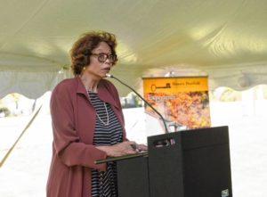Pat Wilson Pheanious speaking at a podium under a tent during an outdoor event.