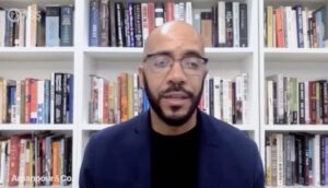 Clint Smith speaking in front of a bookshelf on a PBS show, Amanpour & Co.