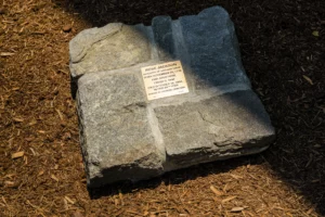 Stone monument with inscription for Rose Jackson, honoring her life and freedom, set on a bark-covered ground.