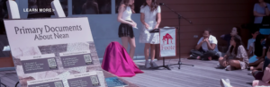 Outdoor presentation on Primary Documents About Nean at Foote School with students and poster display.
