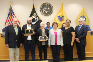 People receiving awards at a Somerset County ceremony with flags and seal in the background.