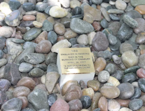 Memorial plaque for Ned, enslaved in Redding, honoring his death in the 1777 Burning of Danbury amidst river stones.