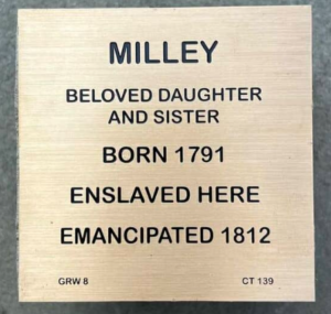 Plaque honoring Milley: Beloved daughter, enslaved here, born 1791, emancipated 1812. Reflects historical legacy.