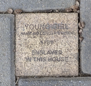 Commemorative sidewalk plaque remembering an unknown young girl enslaved in 1767.
