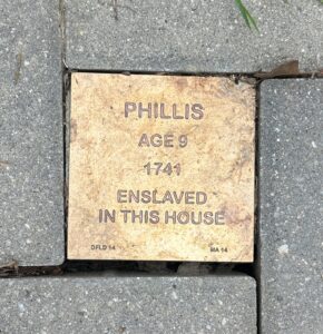 Commemorative plaque for Phillis, age 9, enslaved in 1741, embedded in a brick pathway.