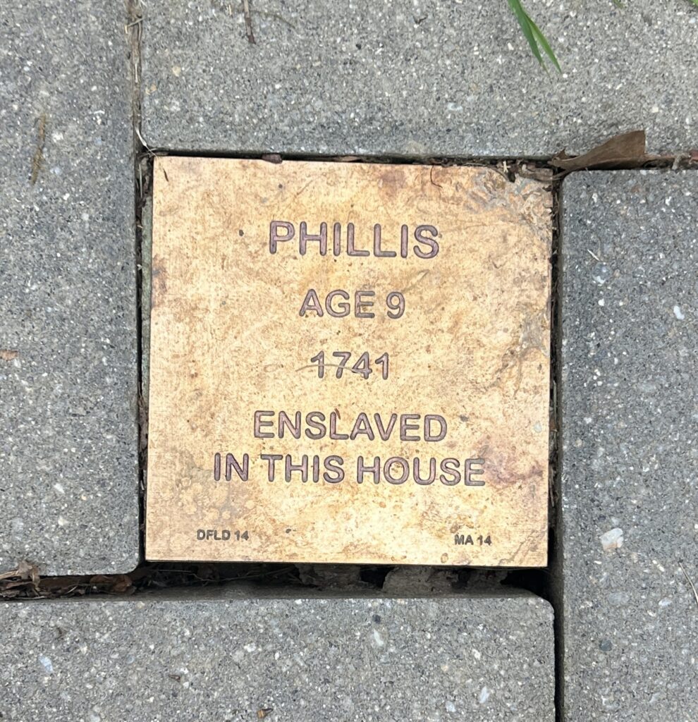 Commemorative plaque for Phillis, age 9, enslaved in 1741, embedded in a brick pathway.