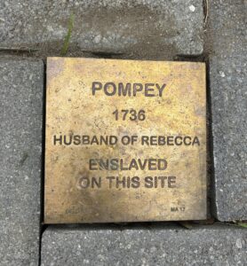 Bronze plaque for Pompey, enslaved in 1736, husband of Rebecca, located on historic site pavement.