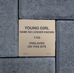 Plaque commemorating an enslaved young girl, name unknown, from 1742, set in stone pavement.