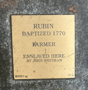 Plaque for Rubin, baptized 1770, enslaved farmer under John Whitman, highlighting historical slavery.