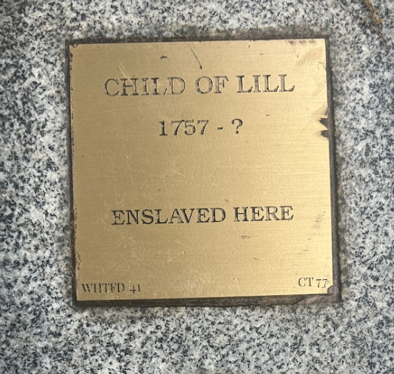 Bronze plaque reading Child of Lill, 1757 - ?, Enslaved Here on a stone base, representing historical remembrance.