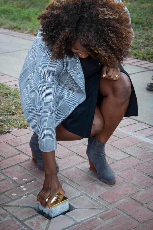 A photo of a woman, Hattie, placing a Witness Stone into a brick walkway.