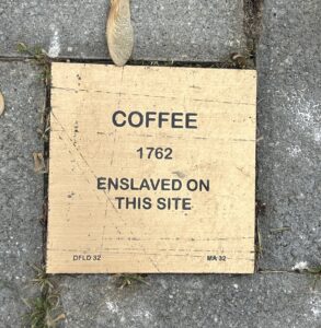 Historical plaque commemorating an enslaved individual named Coffee from 1762 on this site.