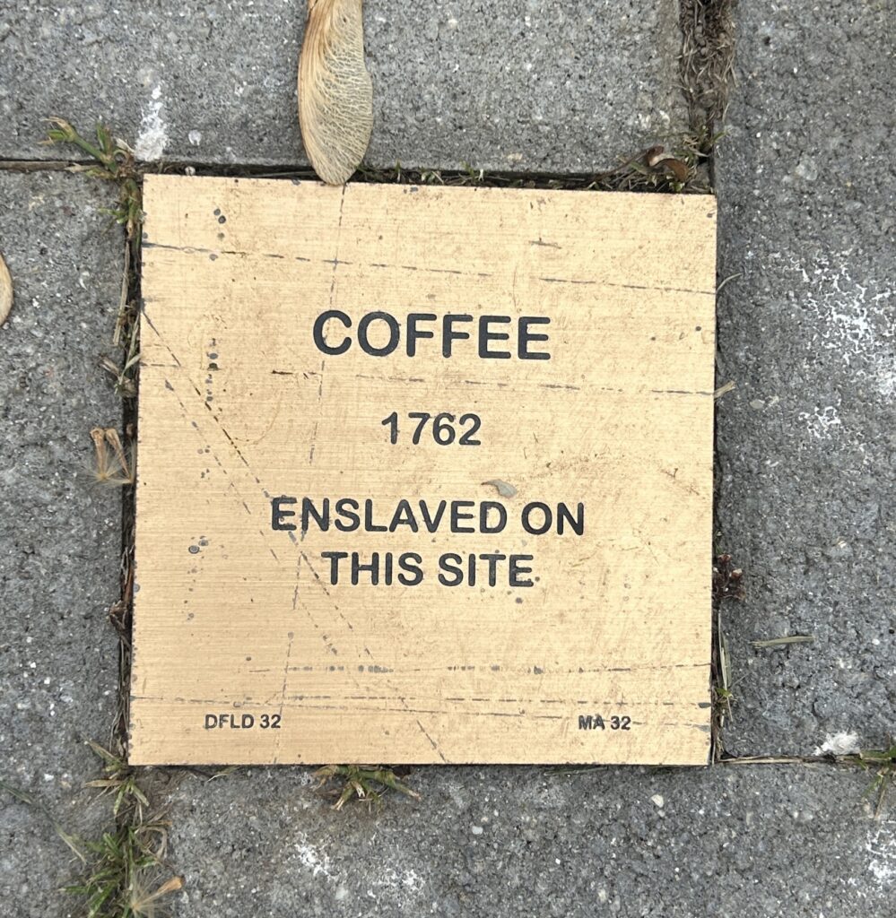 Historical plaque commemorating an enslaved individual named Coffee from 1762 on this site.