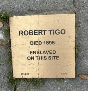 Commemorative plaque for Robert Tigo, enslaved and died 1695, on site. A historical marker on pavement.