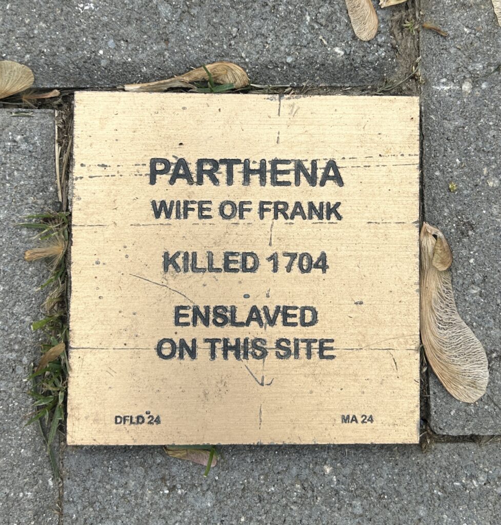 Memorial plaque for Parthena, enslaved and killed in 1704, highlighting historical injustice at site.