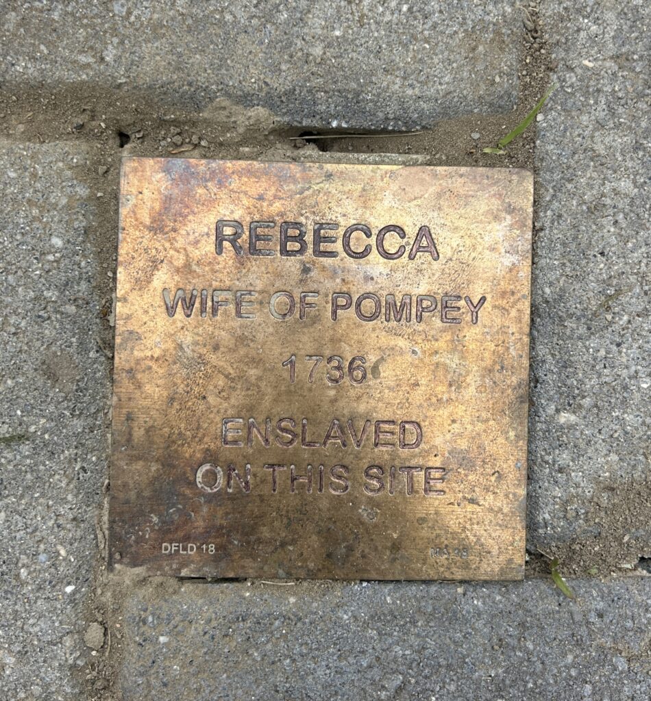 Commemorative plaque for Rebecca, wife of Pompey, acknowledging her enslavement in 1736 at this site.