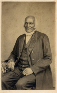 Vintage portrait of a distinguished elderly man in a formal suit, sitting, with a neutral background.