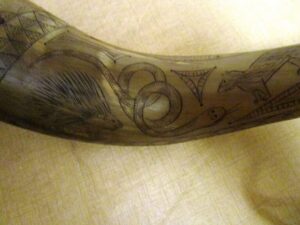 Intricately carved animal motifs on a wooden ceremonial horn with distinctive designs.