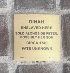 Memorial plaque for Dinah, enslaved circa 1740, mentions her son Peter. Fate unknown. Brick wall background.