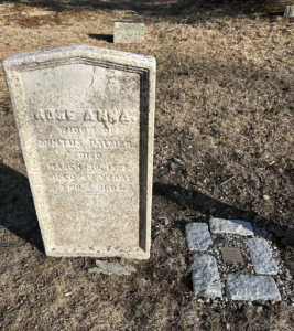 Historic gravestone in a cemetery marking the resting place of a person who passed away in 1863, surrounded by grass.