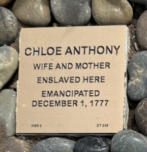 Engraved stone commemorating Chloe Anthony, emancipated on December 1, 1777, surrounded by pebbles.
