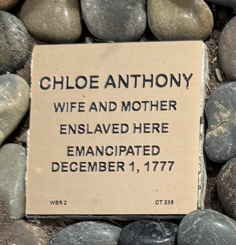 Engraved stone commemorating Chloe Anthony, emancipated on December 1, 1777, surrounded by pebbles.