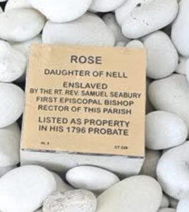 Commemorative plaque for Rose, enslaved by Episcopal Bishop Samuel Seabury, positioned among white stones.